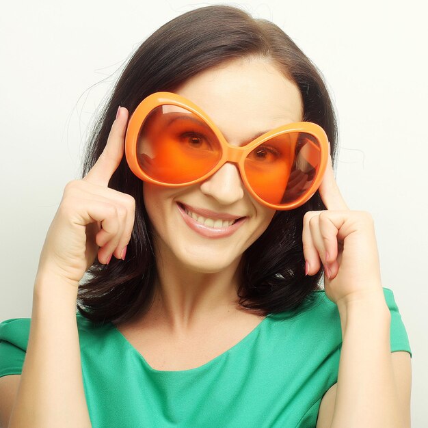 Young happy woman with big orange sunglasses studio shot