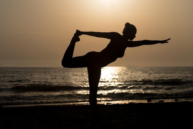 Young Healthy Woman Practicing Yoga Fitness Exercise on the Beach at Sunset  Healthy Lifestyle Concept  Copy Space Text