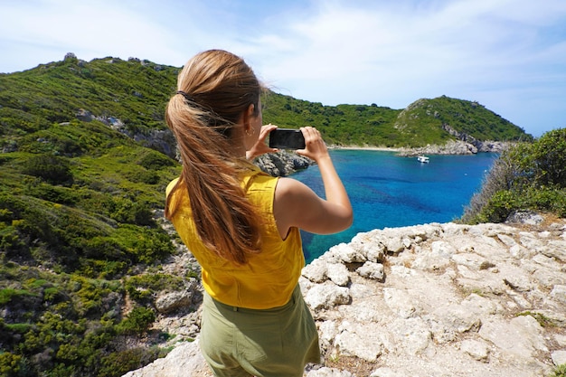 Young hiker explorer girl taking picture with smartphone of natural tropical panoramic view Wide angle Windy day