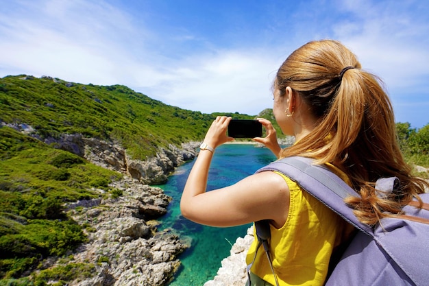 Young hiker girl taking photo with smartphone of natural tropical landscape Wide angle