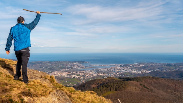 A young hiker looking at the views of the towns of Hondarribia and Hendaya from the mountains of Aiako Harria or PeÃ±as de Aya, GuipÃºzcoa