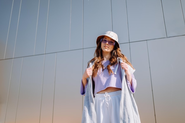 Young hip hop girl in oversize outfit wearing dancing into music minimalistic urban background