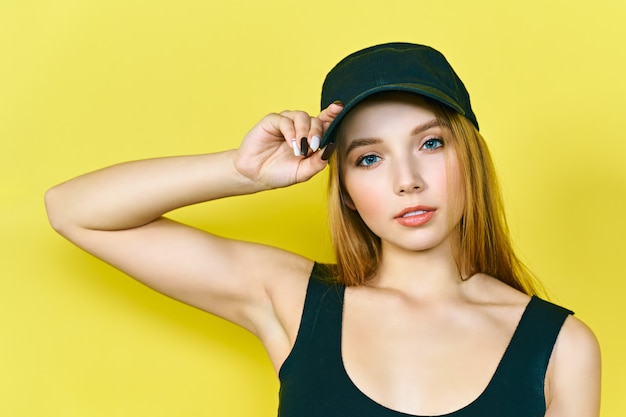 young hip hop woman in cap. On a yellow background.