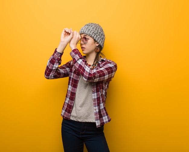 Young hippie natural woman making the gesture of a spyglass