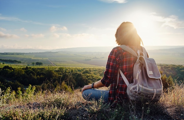 Young hipster girl enjoy sunset on viewpoint Travel woman with backpack