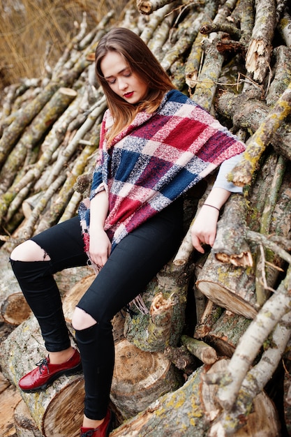 Young hipster girl wear on blanket against wooden stumps on wood.