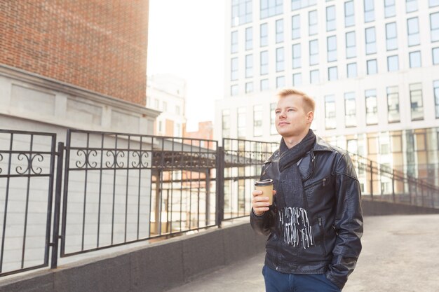 Young hipster man on the street drinking coffee on a sunny day