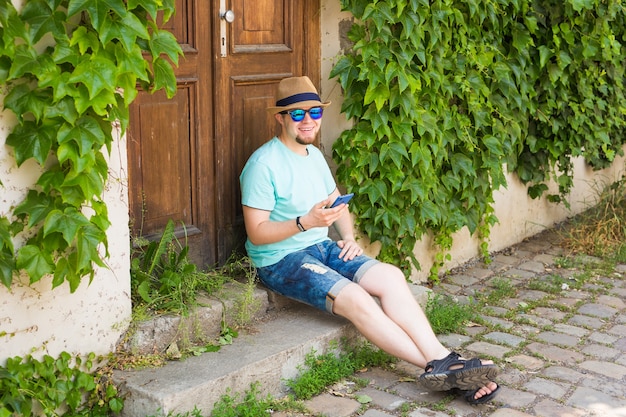 Young hipster man using mobile smart phone outdoors