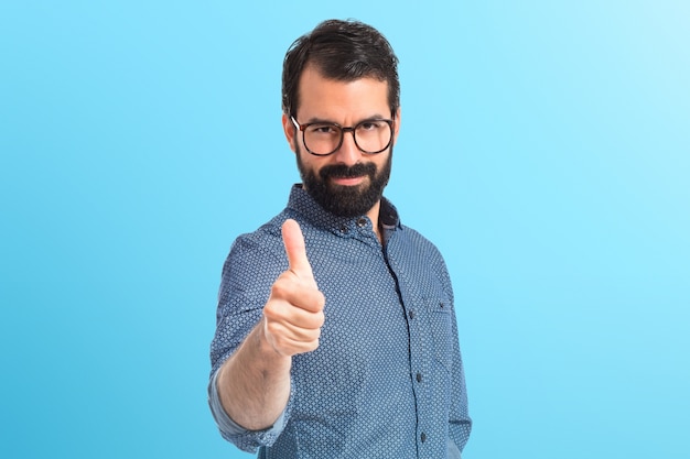 Young hipster man with thumb up on colorful background