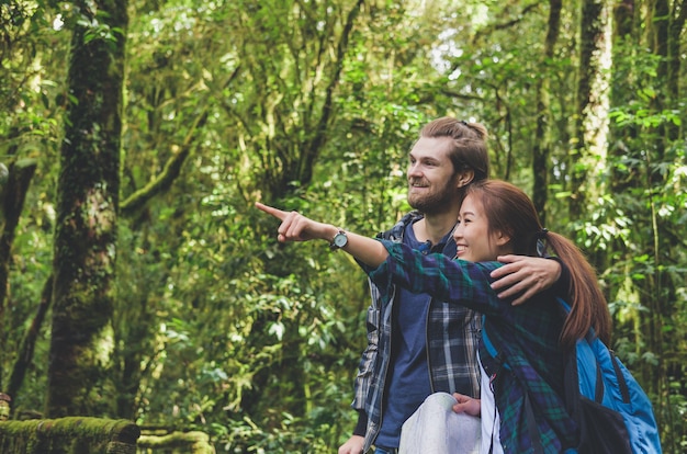 Young hipster traveler Couple with backpack hiking in the green forest