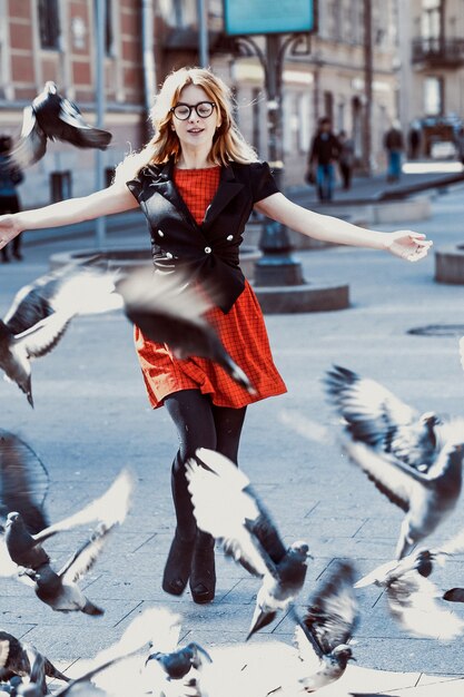 Young hipster woman wearing red dress  in the city. Spring and birds doves.