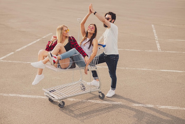 Young hipsters with shopping trolley doing high five