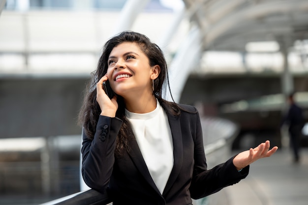 Young Hispanic business woman talking on mobile phone outdoors