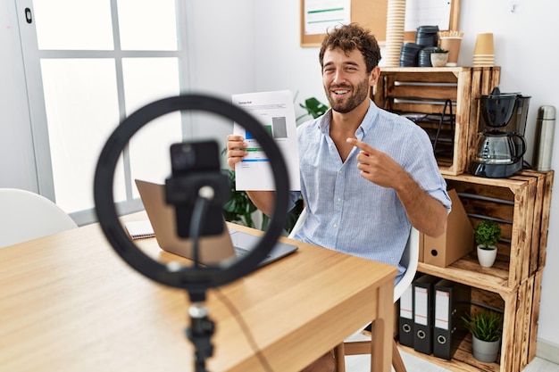 Young hispanic businessman having video call using smartphone at the office.