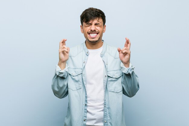 Young hispanic cool man crossing fingers for having luck