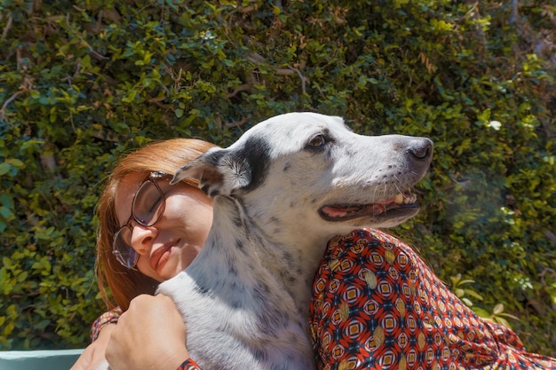 Young Hispanic female chilling with her dog on a bench in a park