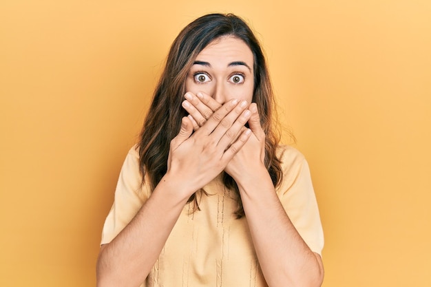 Young hispanic girl wearing casual clothes shocked covering mouth with hands for mistake secret concept