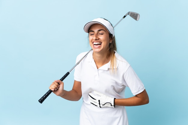 Young hispanic golfer woman over isolated blue wall smiling a lot