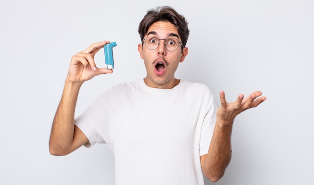 Young hispanic man amazed, shocked and astonished with an unbelievable surprise. asthma concept