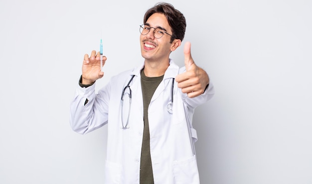 Young hispanic man feeling proud,smiling positively with thumbs up. doctor syringe concept