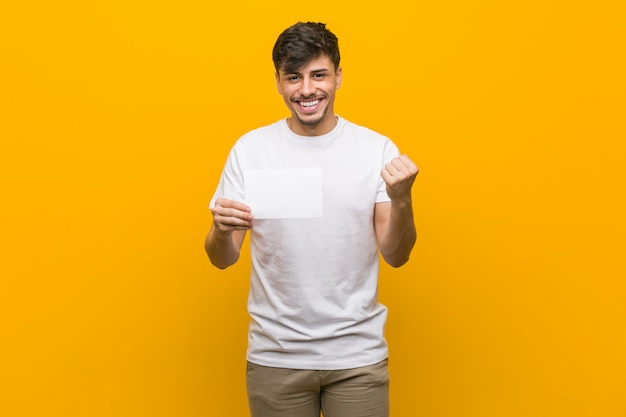 Young hispanic man holding a placard cheering carefree and excited.