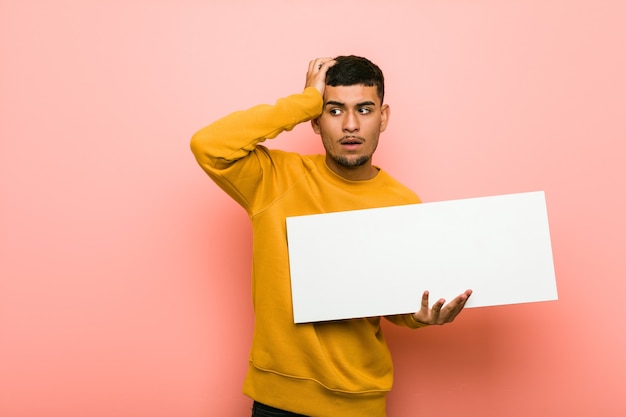 Young hispanic man holding a placard