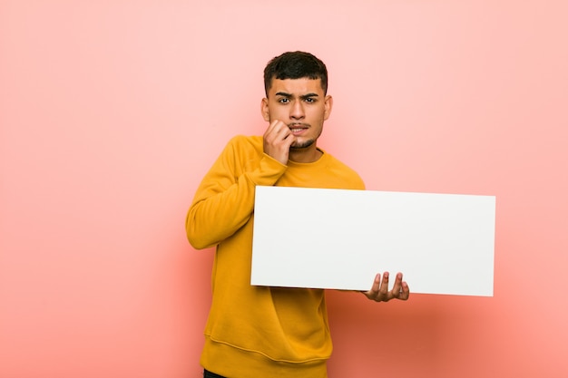 Young hispanic man holding a placard