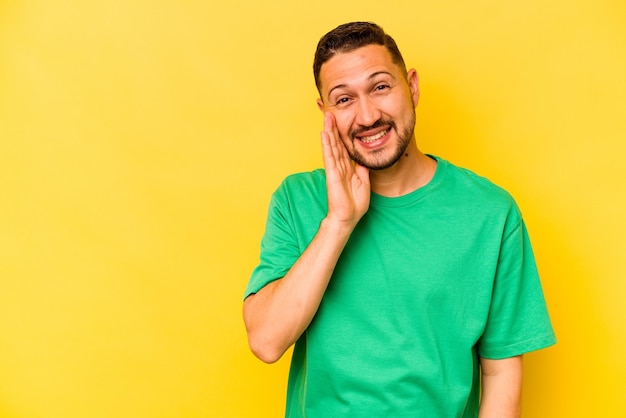 Young hispanic man isolated on yellow background shouts loud keeps eyes opened and hands tense