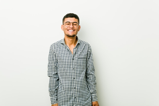 Young hispanic man laughs and closes eyes, feels relaxed and happy.