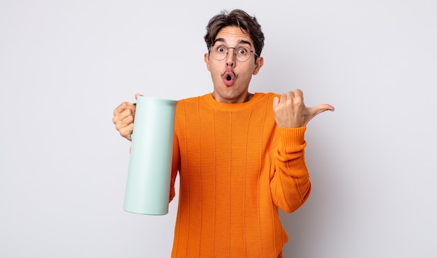 young hispanic man looking astonished in disbelief. thermos concept