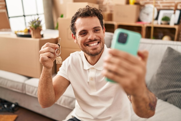 Young hispanic man make selfie by the smartphone holding key at new home