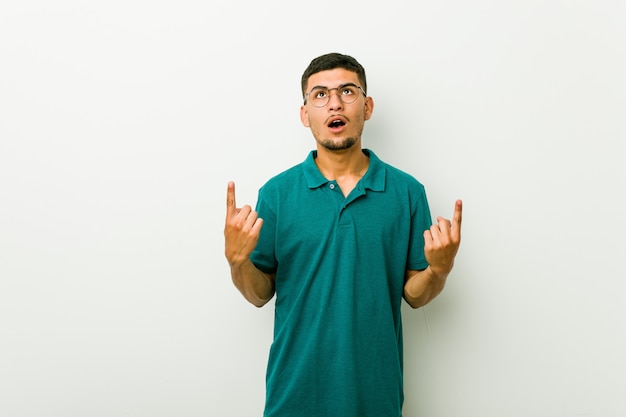 Young hispanic man pointing upside with opened mouth.