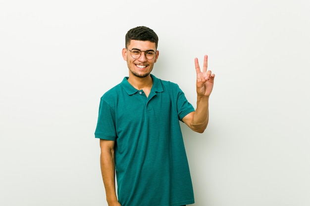 Young hispanic man showing number two with fingers.