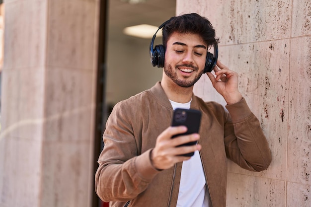 Young hispanic man smiling confident listening to music at street