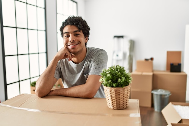 Young hispanic man smiling happy moving at new home.