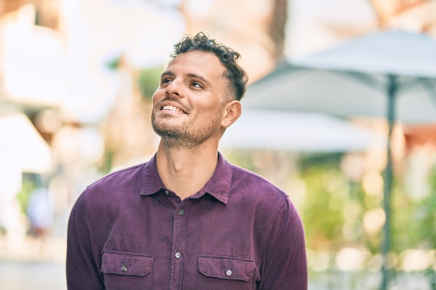 Young hispanic man smiling happy standing at the city.