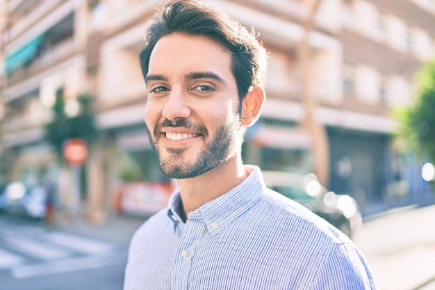 Young hispanic man smiling happy walking at the city