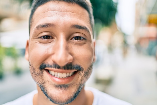 Young hispanic man smiling happy walking at street of city.