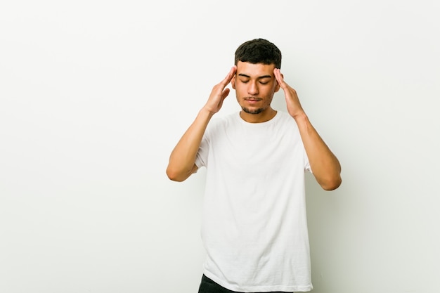 Young hispanic man touching temples and having headache.