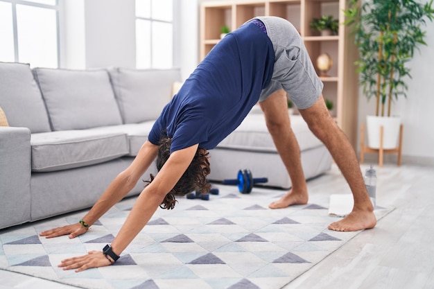 Young hispanic man training yoga at home