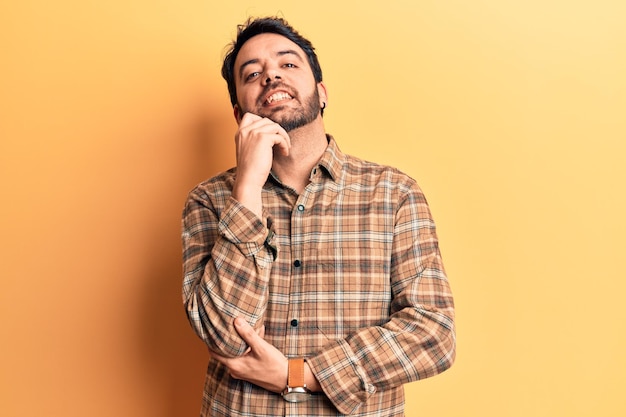 Photo young hispanic man wearing casual clothes smiling looking confident at the camera with crossed arms and hand on chin thinking positive