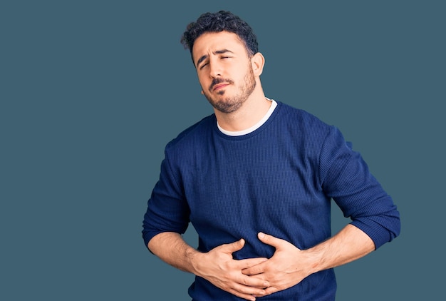 Young hispanic man wearing casual clothes with hand on stomach because indigestion painful illness feeling unwell ache concept