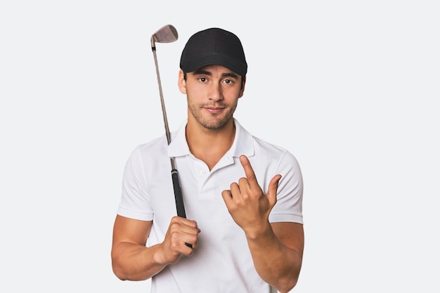 Photo young hispanic man with golf club pointing with finger at you as if inviting come closer