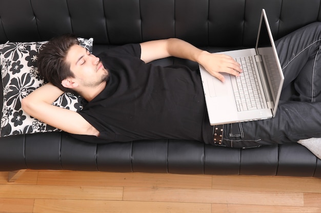 A young hispanic man with a laptop on the Sofa.