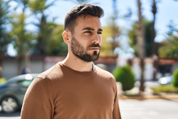 Young hispanic man with relaxed expression standing at park