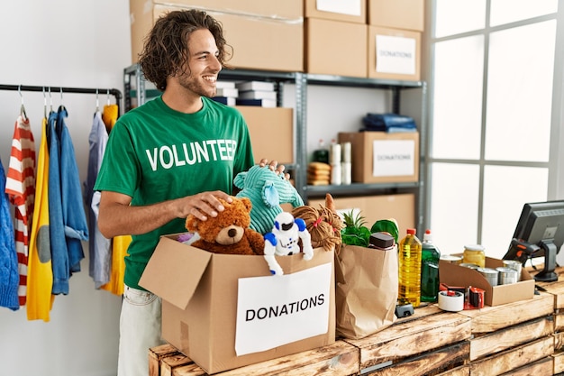 Young hispanic volunteer man smiling happy working at charity center.