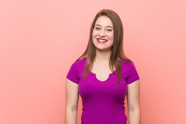 Young hispanic woman against a pink wall happy, smiling and cheerful.