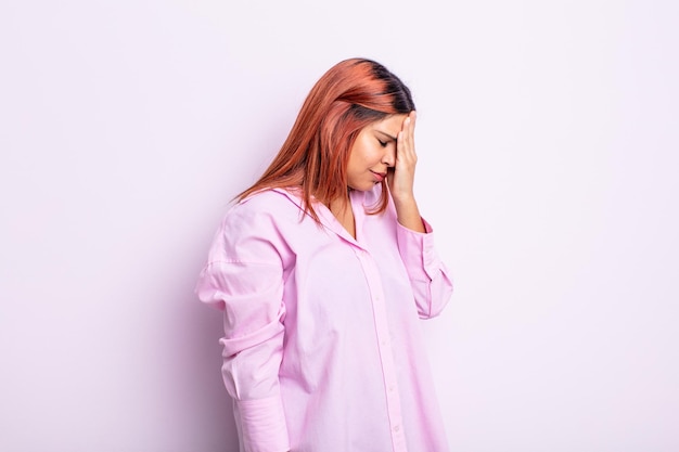 young hispanic woman covering eyes with hands with a sad, frustrated look of despair, crying, side view