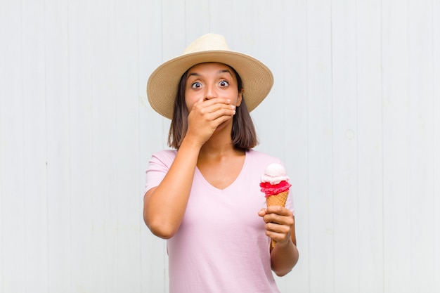 Young hispanic woman covering mouth with hands with a shocked, surprised expression, keeping a secret or saying oops