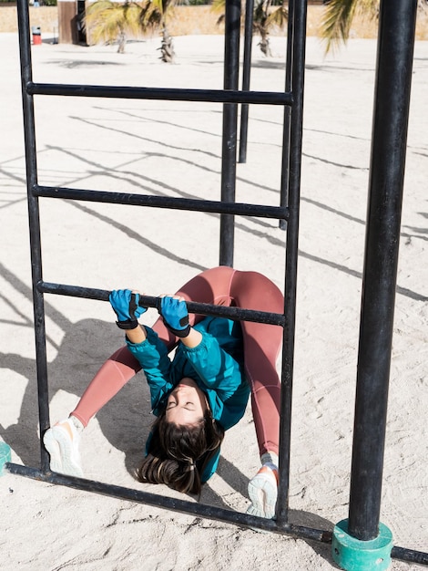 Young hispanic woman doing flexibility exercise at the espalier